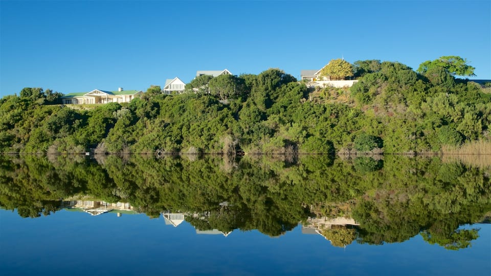 A serene lake with a reflection of houses and trees.