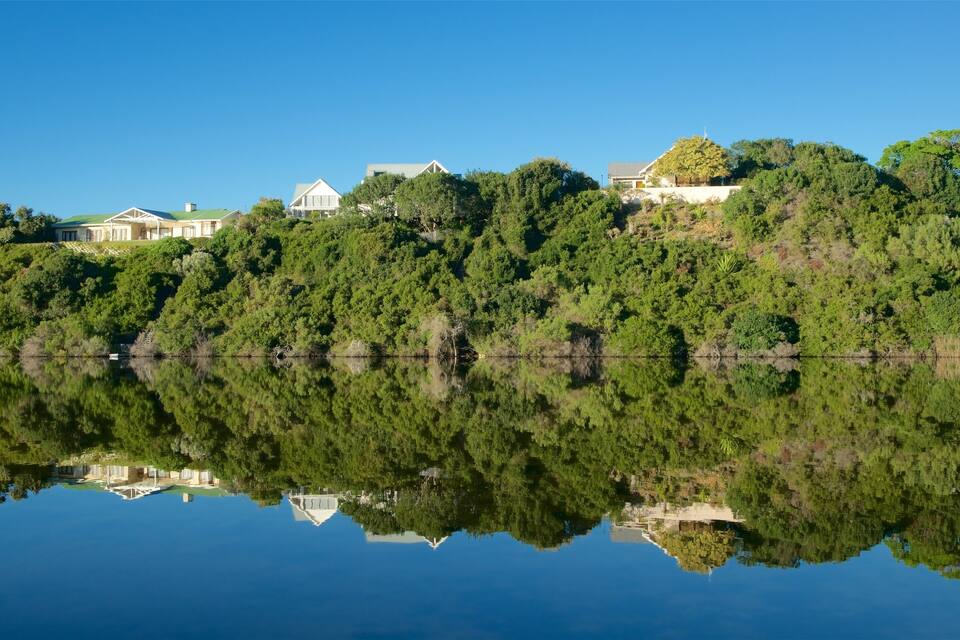 A serene lake with a reflection of houses and trees.