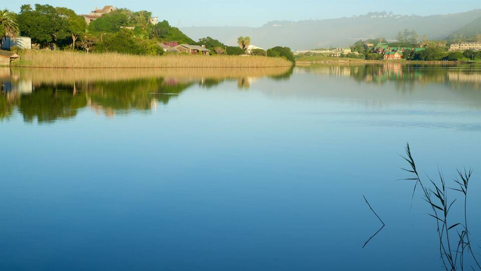 A calm lake with reflections of houses and trees.