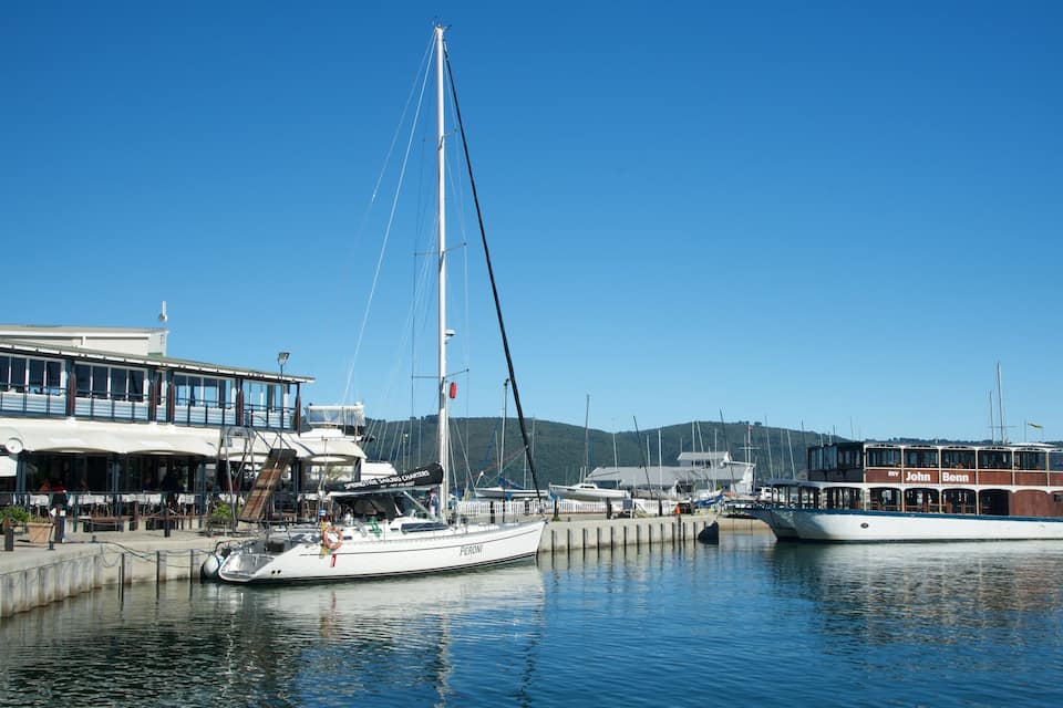 Un port esportiu amb embarcacions amarrades, un edifici amb la senyalització 'Springtime Sailing Charters' i una collada al fons.