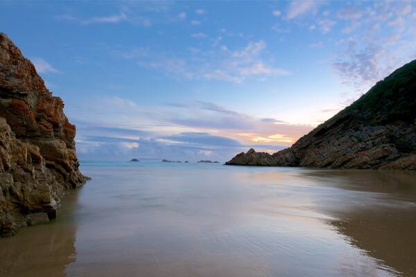 A coastal landscape with rocky cliffs and calm waters.