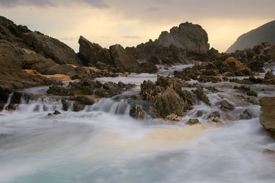 A rocky landscape with a flowing river and a waterfall.
