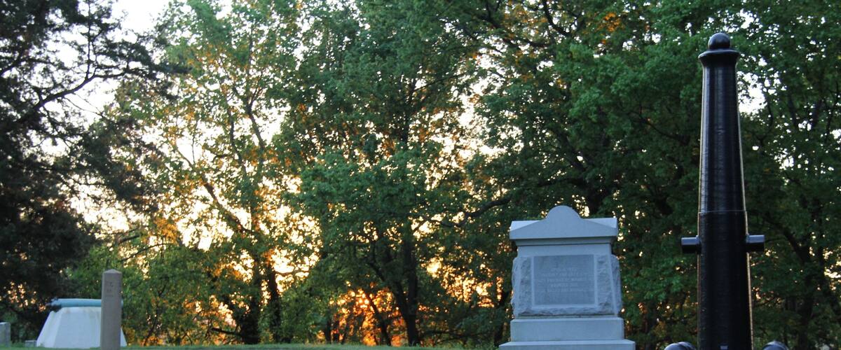 En kyrkogård med gravstenar av sten och ett högt monument.