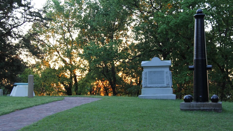 A cemetery with stone headstones and a tall monument.