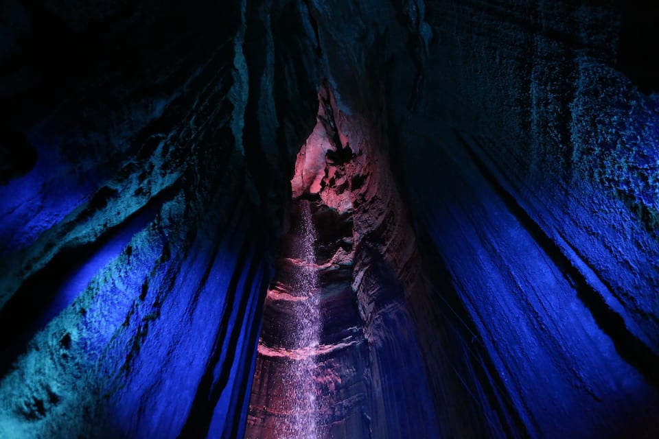 Une grotte étroite et éclairée, avec un éclairage bleu et rose.