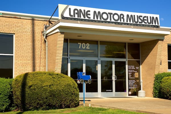 Lane Motor Museum bygningen med en blå model af en veteranbil foran.
