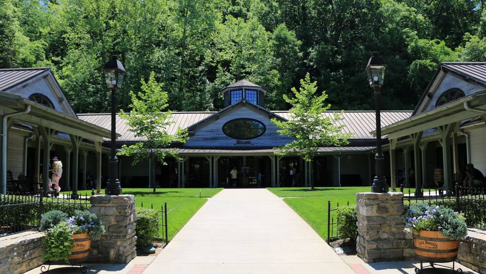 A building with a blue roof and a clock, surrounded by trees and a pathway leading to it.