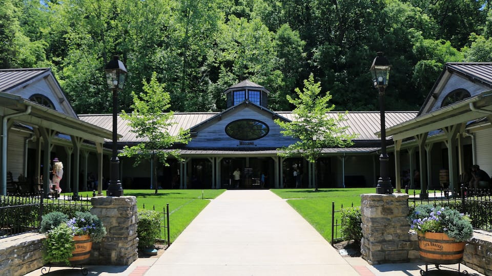 A building with a blue roof and a clock, surrounded by trees and a pathway leading to it.
