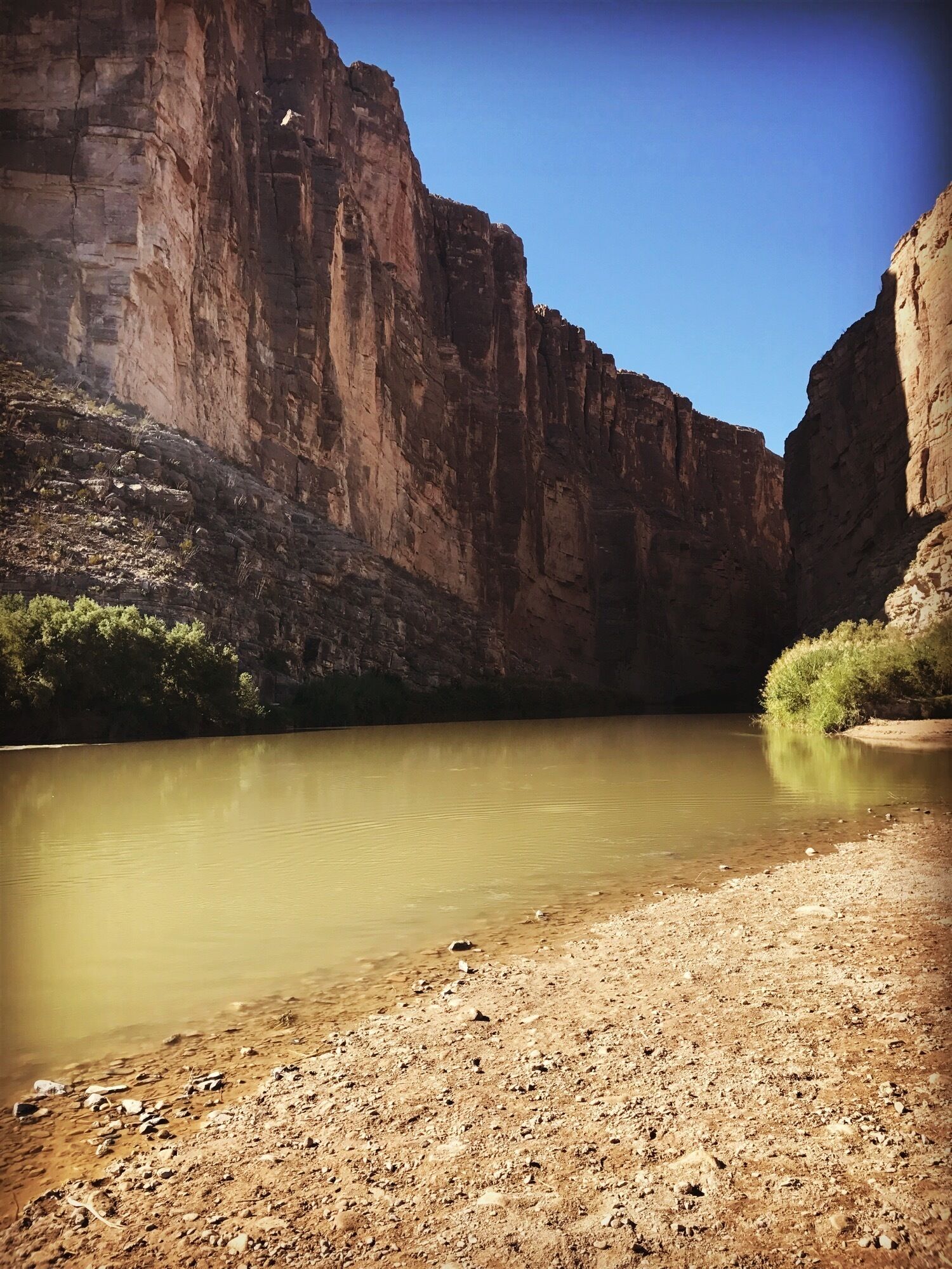 A canyon with a calm river and rocky terrain.