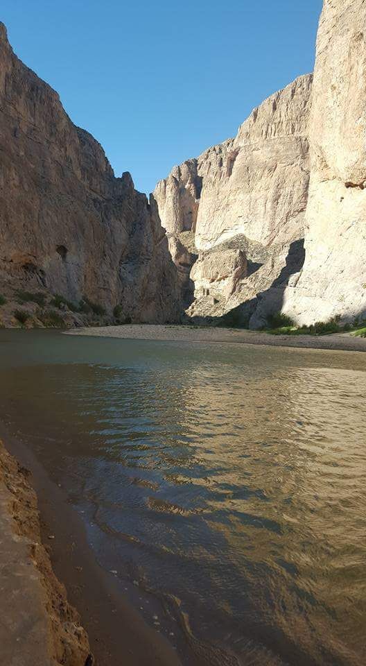 A canyon with steep cliffs and a calm river.