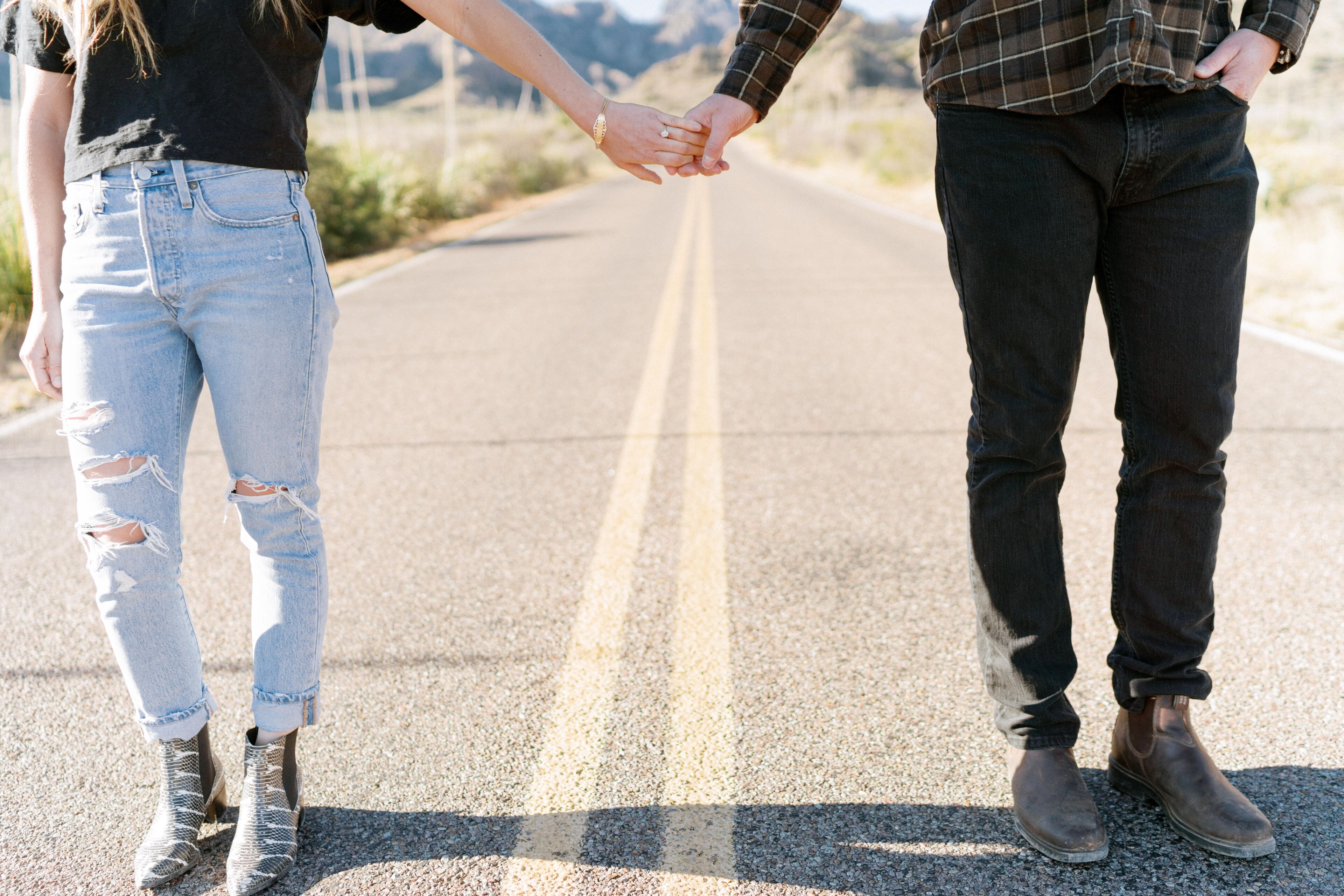 A man and woman holding hands on a road that leads to the Chisos