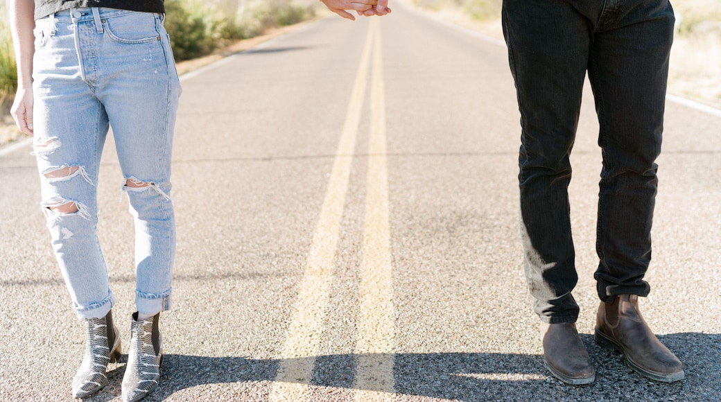 A man and woman holding hands on a road that leads to the Chisos
