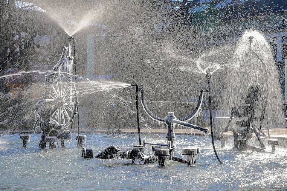 A fountain with water jets in a snowy park.