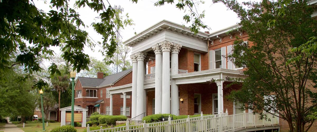 A historic building with a brick facade, white columns, and a covered porch.