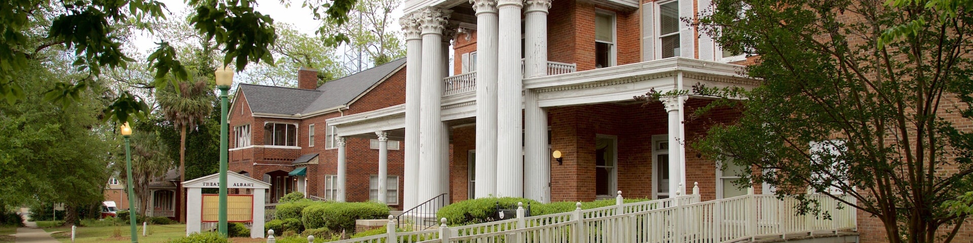 A historic building with a brick facade, white columns, and a covered porch.