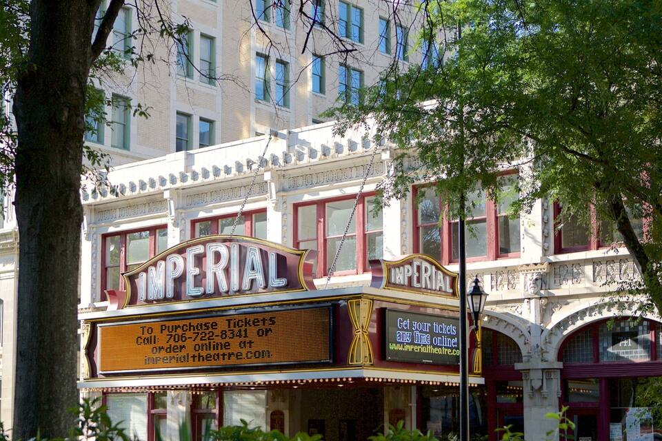 Un théâtre avec une enseigne lumineuse indiquant « IMPÉRIAL » et un panneau numérique affichant les informations sur les billets.