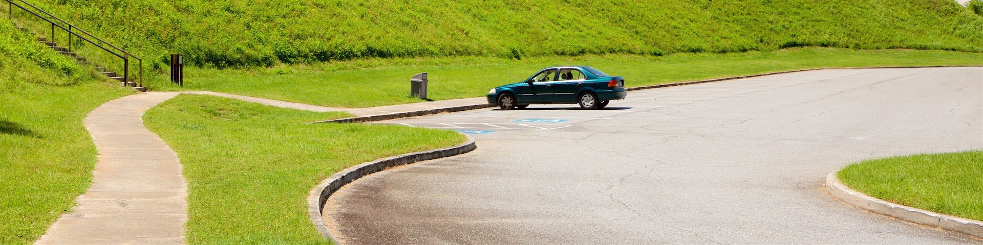 A car on a winding road with grassy hills in the background.