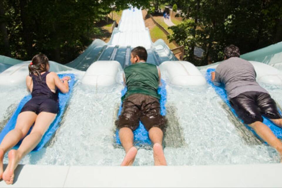 Three people lying on water slides at a water park.