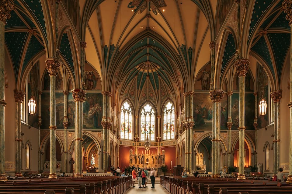 A cathedral interior with high vaulted ceilings, stained glass windows, and ornate columns.