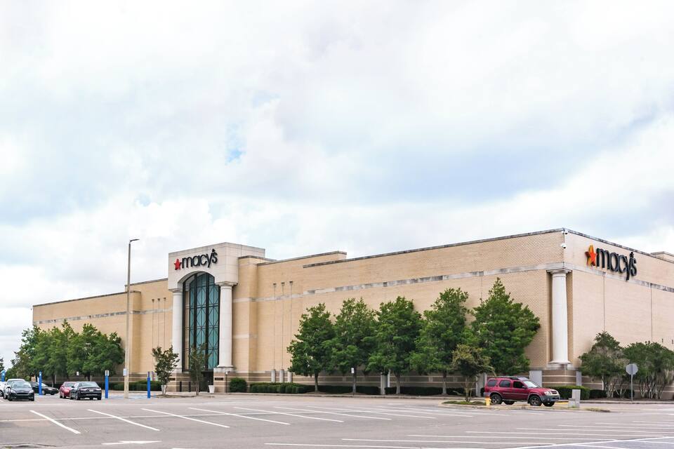 Una gran tienda Macy's con una entrada destacada y estacionamiento.