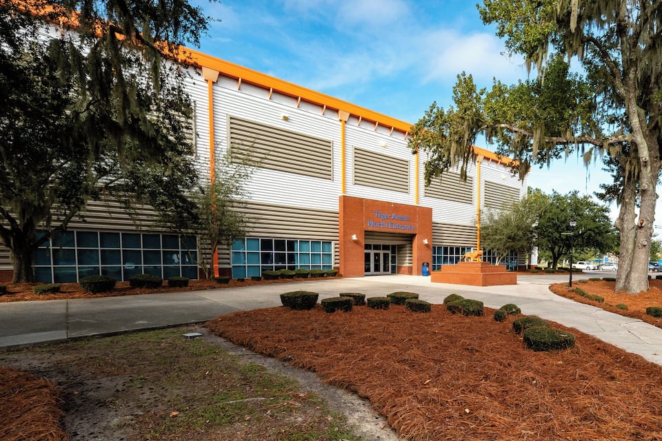 A building with a sign reading "Tiger Arm North Entrance" and a landscaped area with trimmed bushes.