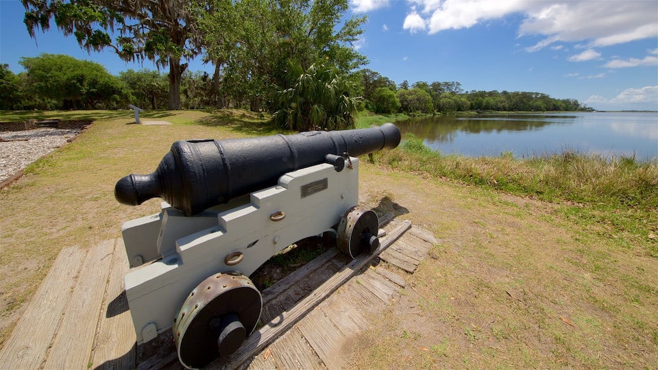 A cannon on a wooden platform by a lake.