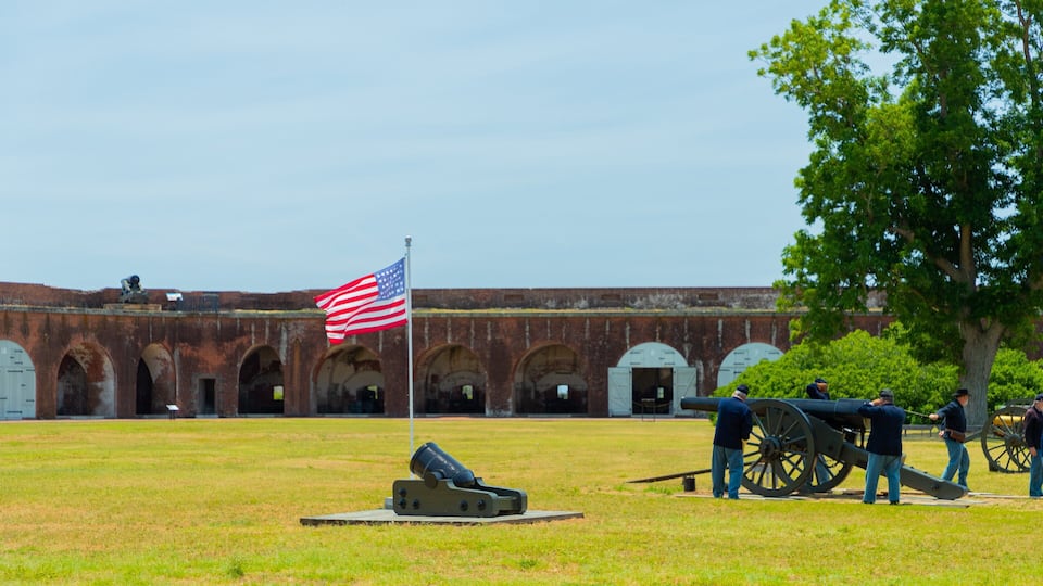 A historic fort with a flagpole, cannons, and a large tree.