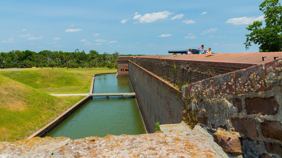 A historic fort with a moat, brick walls, and a cannon.