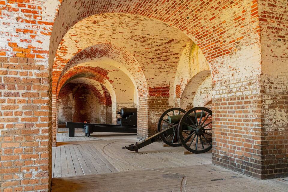 An interior with brick arches and cannons.