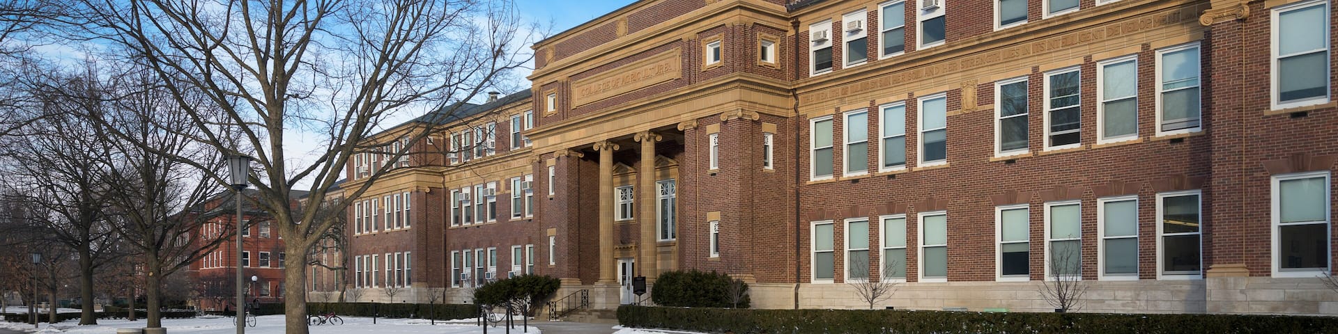 A large brick building with multiple windows and a snow-covered ground.