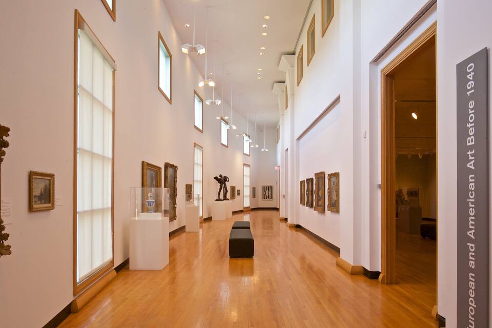 Una galería de arte con suelos de madera, cuadros enmarcados y una escultura.