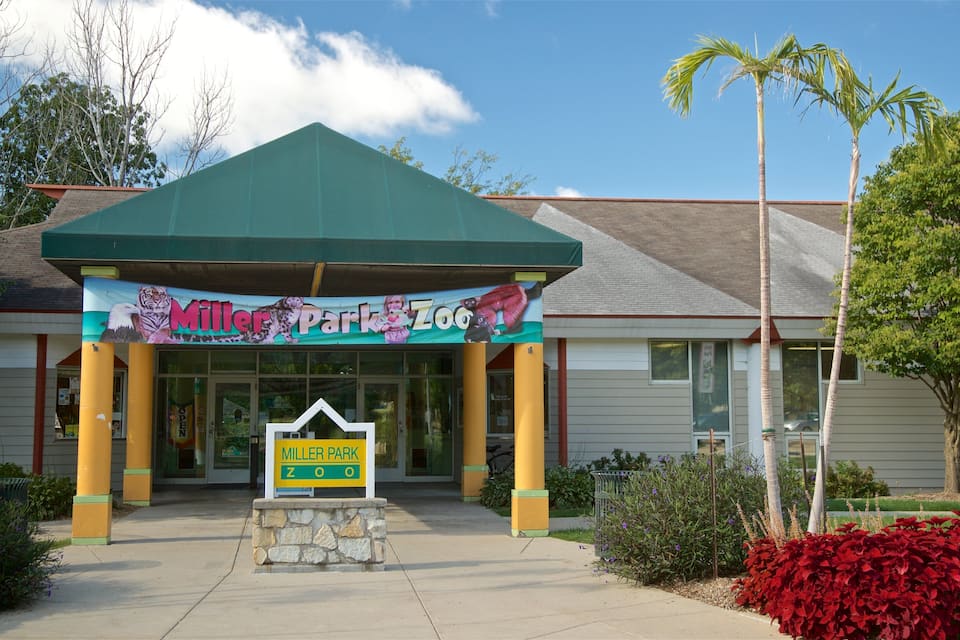 The entrance to the Miller Park Zoo, featuring a green roof, yellow pillars, and a signboard.