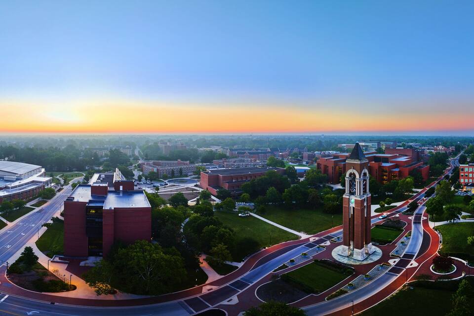 A university campus with a prominent clock tower, a large dome building, and a circular road interchange.