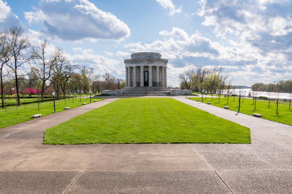 A large, circular building with columns, surrounded by a well-maintained lawn and pathways.