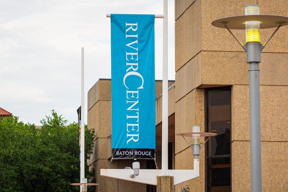 Uma faixa com os dizeres 'RIVERCENTER' e 'BATON ROUGE' pendurada em um edifício.