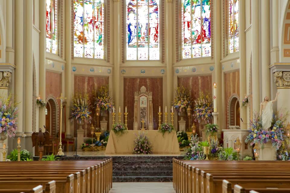 Interior de iglesia con vidrieras, altar y bancos.