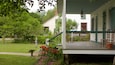 A white house with a green porch, red door, and a wooden fence.