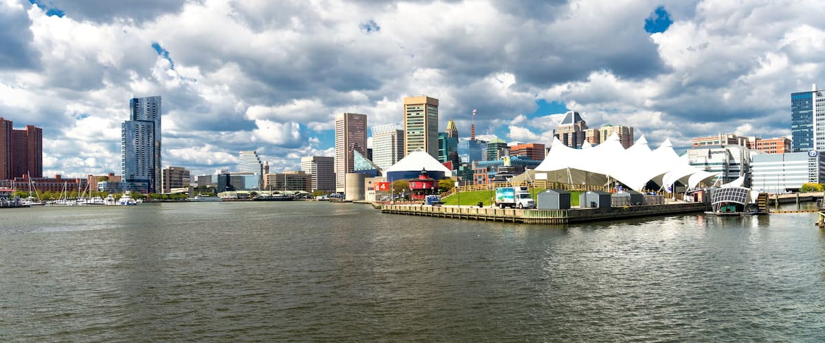 Panoramic view of the Baltimore Pier and Inner Harbor and skyscrapers against a blue sky with low clouds.