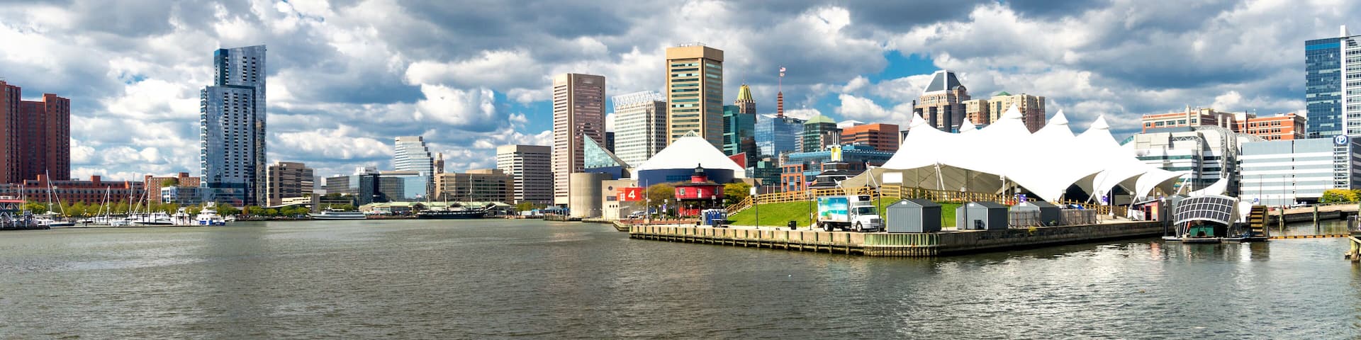 Panoramic view of the Baltimore Pier and Inner Harbor and skyscrapers against a blue sky with low clouds.