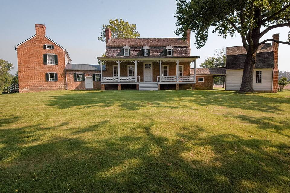 A large brick house with a porch and a lawn in front.