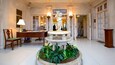 A lobby with a marble fountain, a desk, chairs, and a statue.