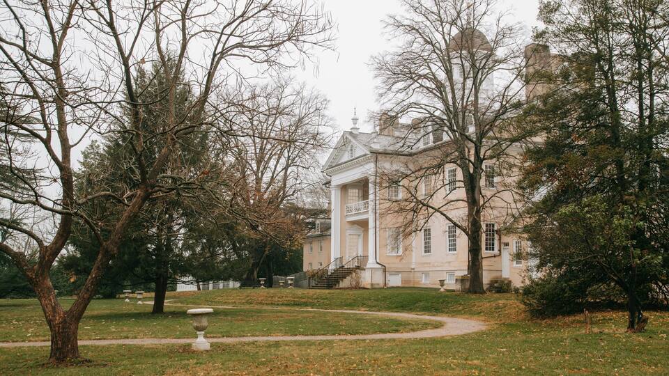 A large, historic building with a grand entrance and a well-maintained lawn.