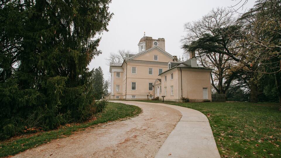 A large, historic building with a prominent tower and a curved driveway leading to it.