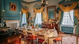 Une salle à manger avec une table dressée pour le repas, des murs bleus et un lustre.