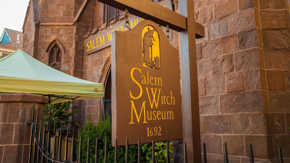A sign for the Salem Witch Museum with a witch silhouette.