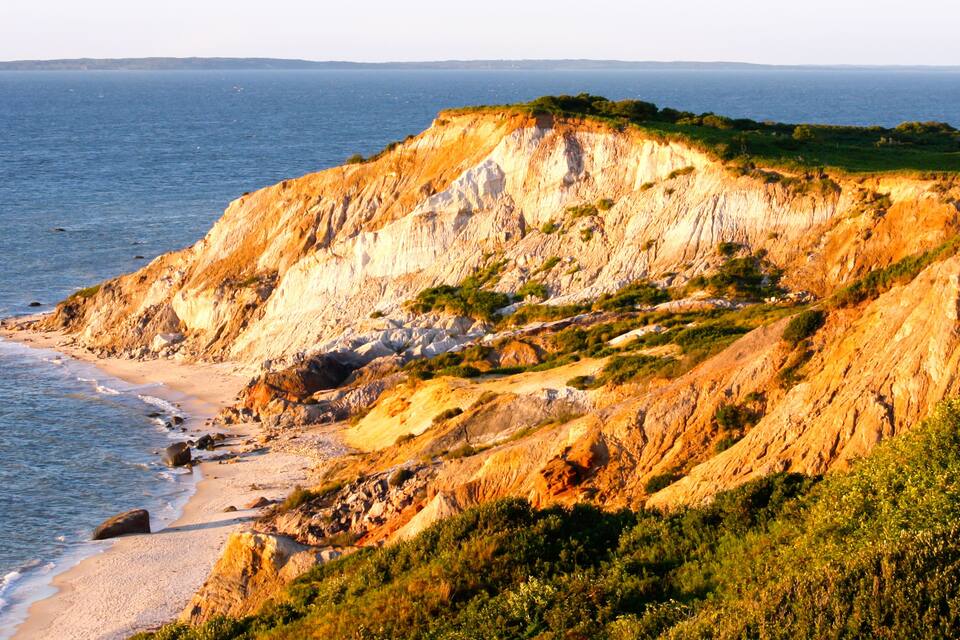 Une falaise côtière avec une plage de sable et l’océan.
