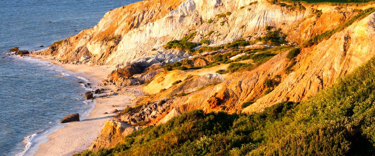 A coastal cliff with a sandy beach and the ocean.