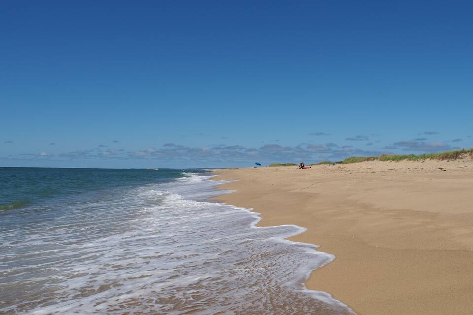 A sandy beach with gentle waves and a clear blue sky.