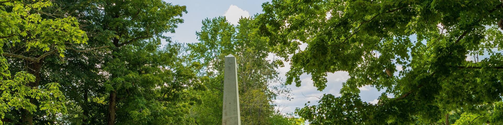 A monument surrounded by lush greenery and a paved walkway.