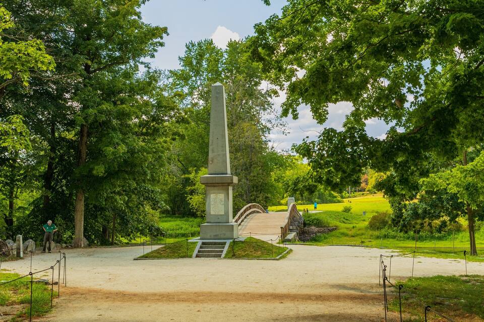 Een monument omringd door weelderige begroeiing en een geplaveid pad.